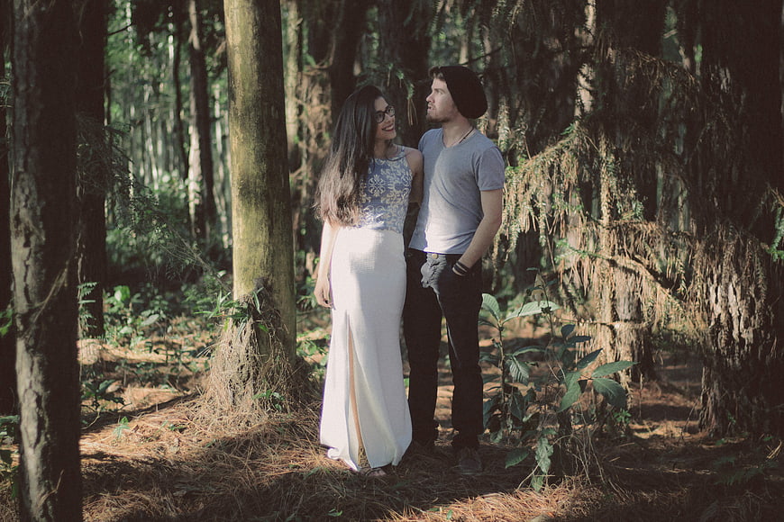 Happy couple smiling and talking in a sunlit forest