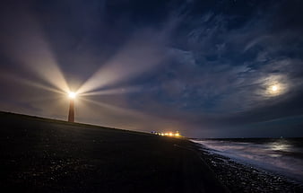 Lighthouse Beam at Night on Dark Beach with Moon