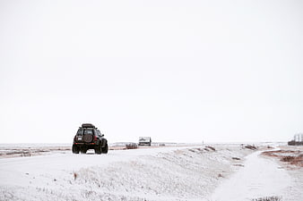 SUV driving on snowy road in winter landscape