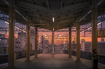 Japanese Train Station Platform At Sunset With Urban Skyline