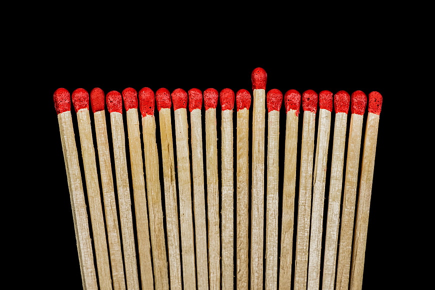 One matchstick stands out among many on black background