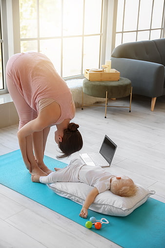 Mother doing yoga while baby sleeps on mat