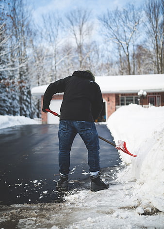 Man Shoveling Snow from Driveway in Winter