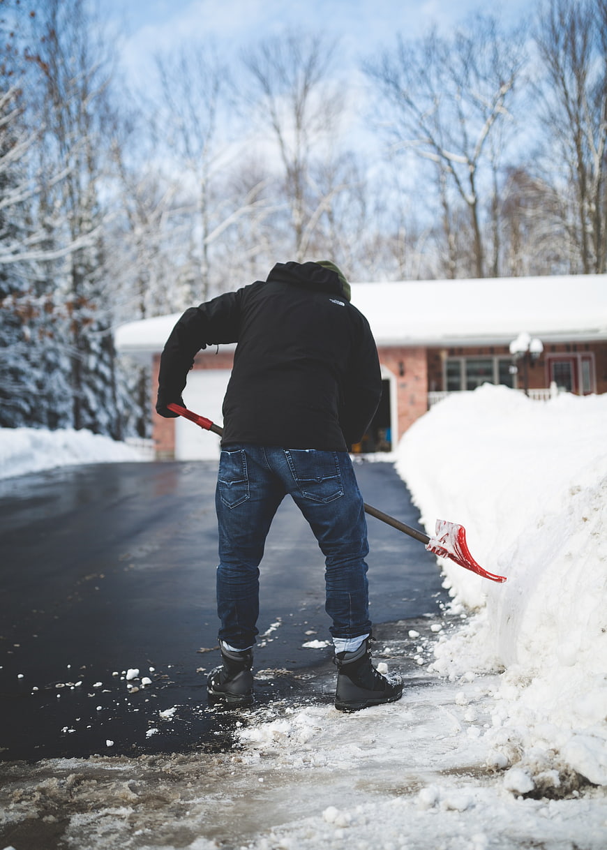 Man Shoveling Snow from Driveway in Winter