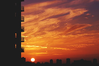 Dramatic orange sunset over city skyline silhouette