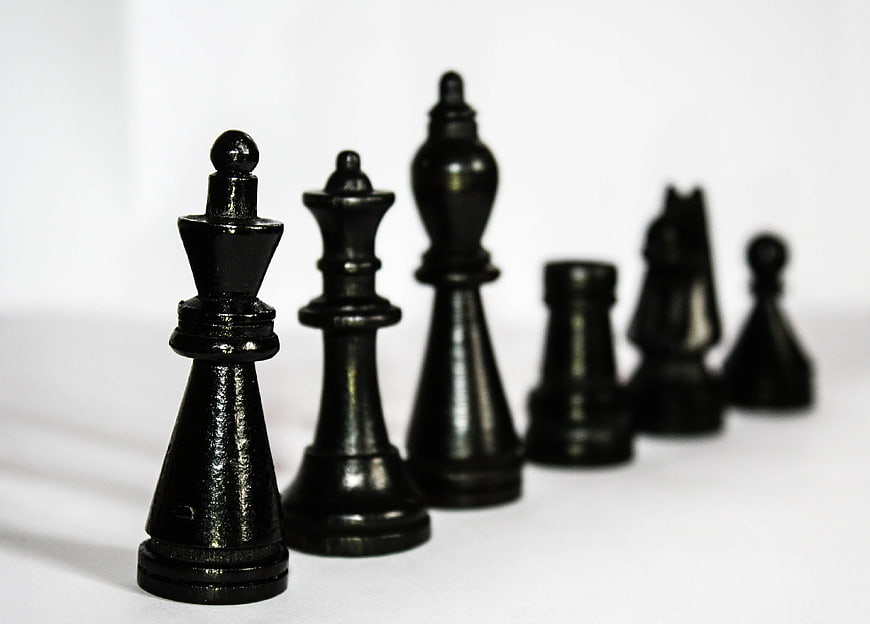 Black Chess Pieces in a Row on White Background