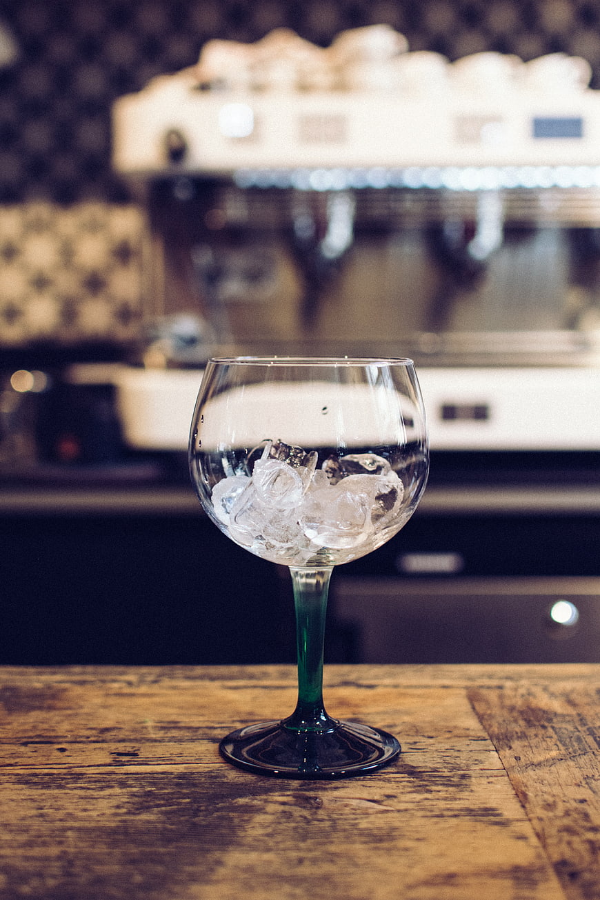 Glass with ice cubes on wooden bar counter