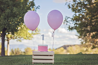 First Birthday Cake with Pink Balloons on Wooden Crate Outdoors