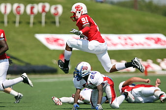American football player leaping over opponent during game