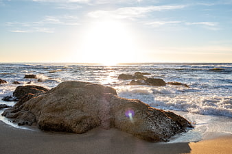 Sunlit Rocky Beach with Ocean Waves at Sunset