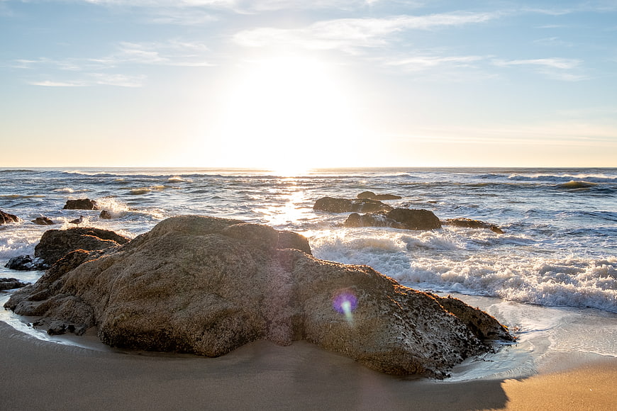 Sunlit Rocky Beach with Ocean Waves at Sunset