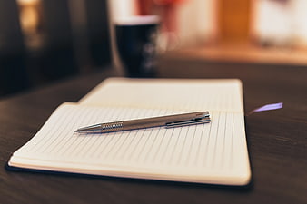 Silver Pen on Open Notebook with Coffee Background