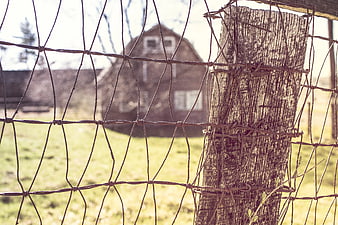 Closeup of Rusty Wire Fence with Barn in Background