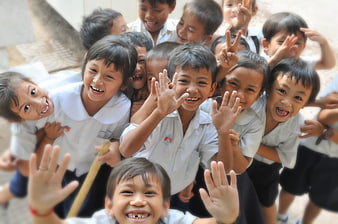 Happy school children waving and smiling at camera