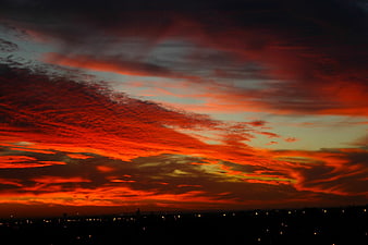 Dramatic fiery red sunset clouds over city skyline