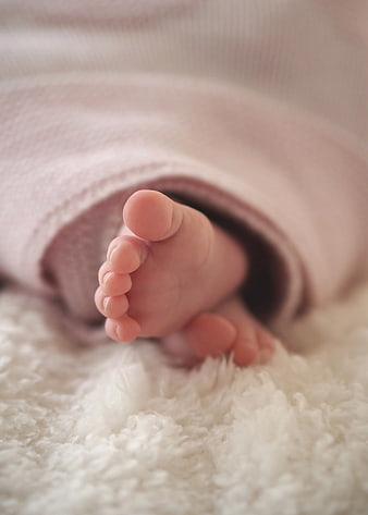 Close-up of tiny baby feet wrapped in soft pink blanket