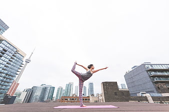 Woman doing yoga on rooftop with city skyline background