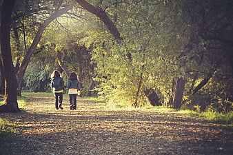 Two Girls Walking Hand in Hand on Forest Trail