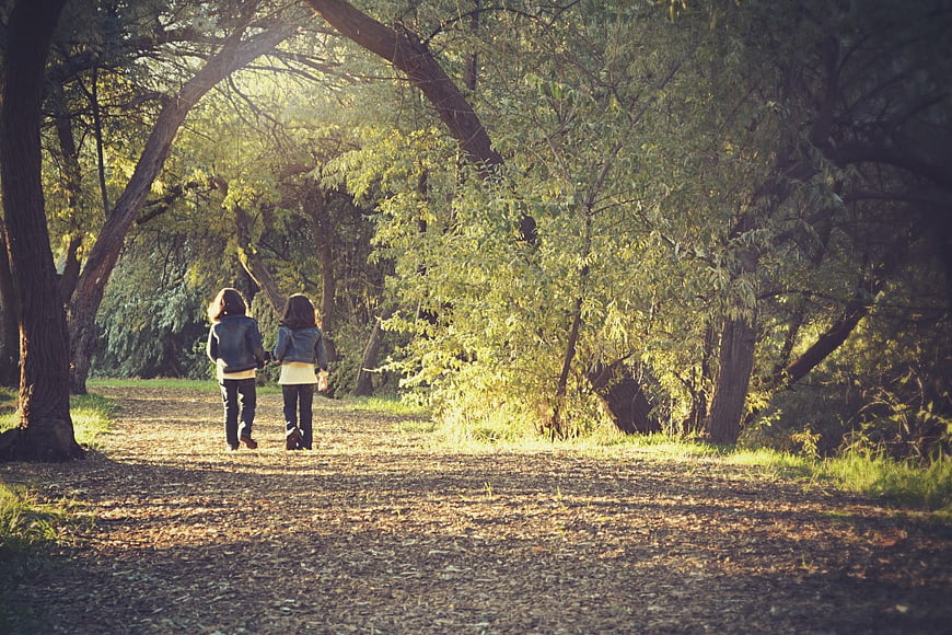 Two Girls Walking Hand in Hand on Forest Trail