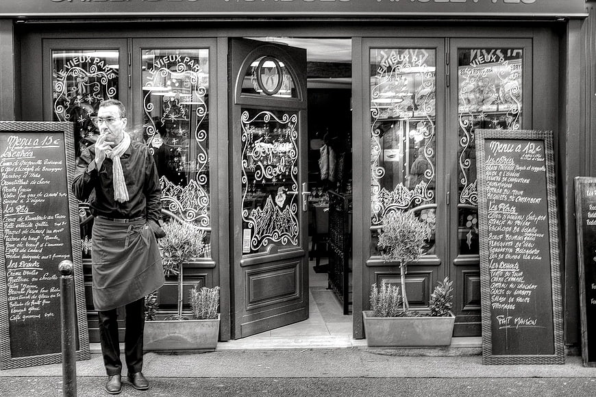 Man Smoking Outside Parisian Restaurant Entrance
