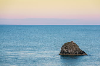 Solitary Rock in Calm Blue Ocean at Sunset