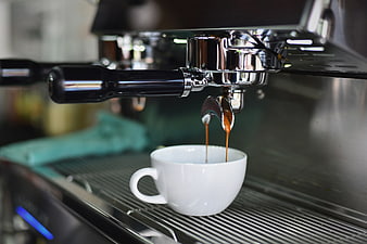 Espresso pouring into white cup from machine