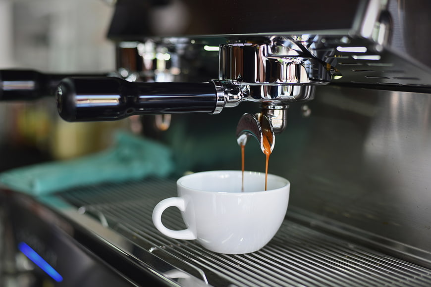 Espresso pouring into white cup from machine