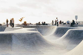 Skateboarder performing aerial trick at concrete skate park