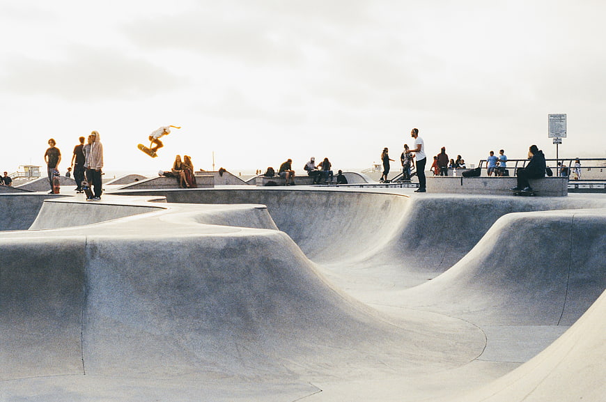 Skateboarder performing aerial trick at concrete skate park