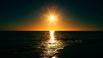 Golden Sunset Over Calm Ocean with Sunburst Reflection