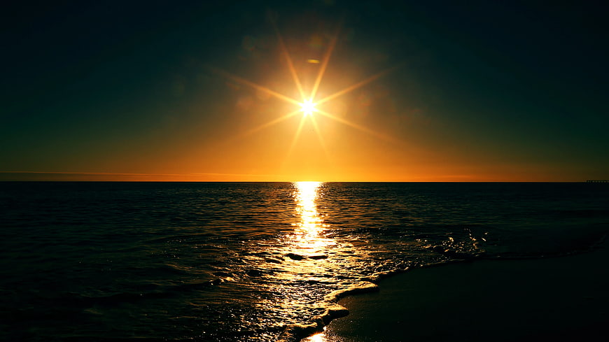 Golden Sunset Over Calm Ocean with Sunburst Reflection