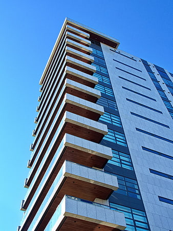 Modern High-Rise Building with Balconies Against Blue Sky
