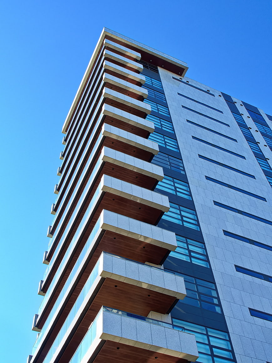 Modern High-Rise Building with Balconies Against Blue Sky