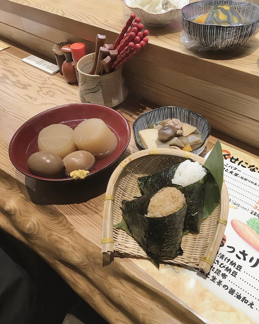 Traditional Japanese Bento with Onigiri and Oden on Wooden Counter