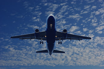 Airplane Landing Under Blue Sky with Clouds
