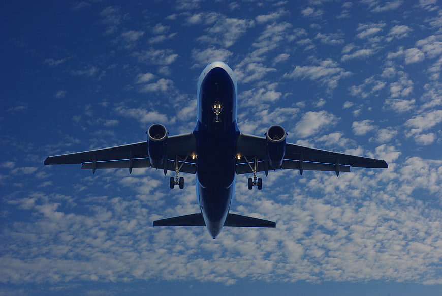 Airplane Landing Under Blue Sky with Clouds
