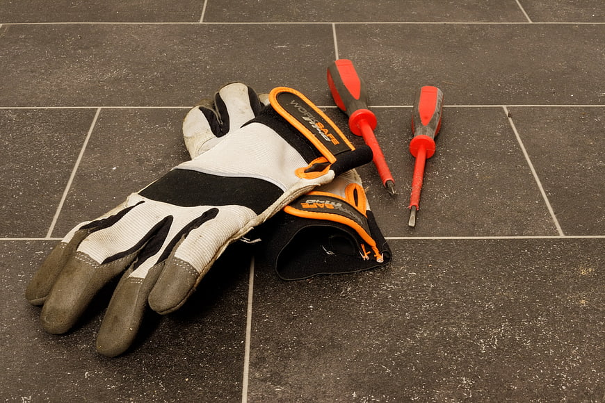 Work Gloves and Screwdrivers on Dark Tiled Surface