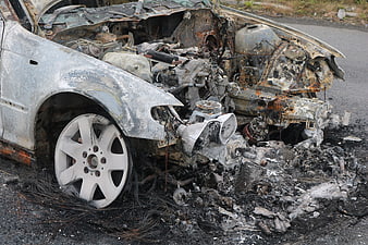 Burnt and wrecked car wreckage on asphalt road