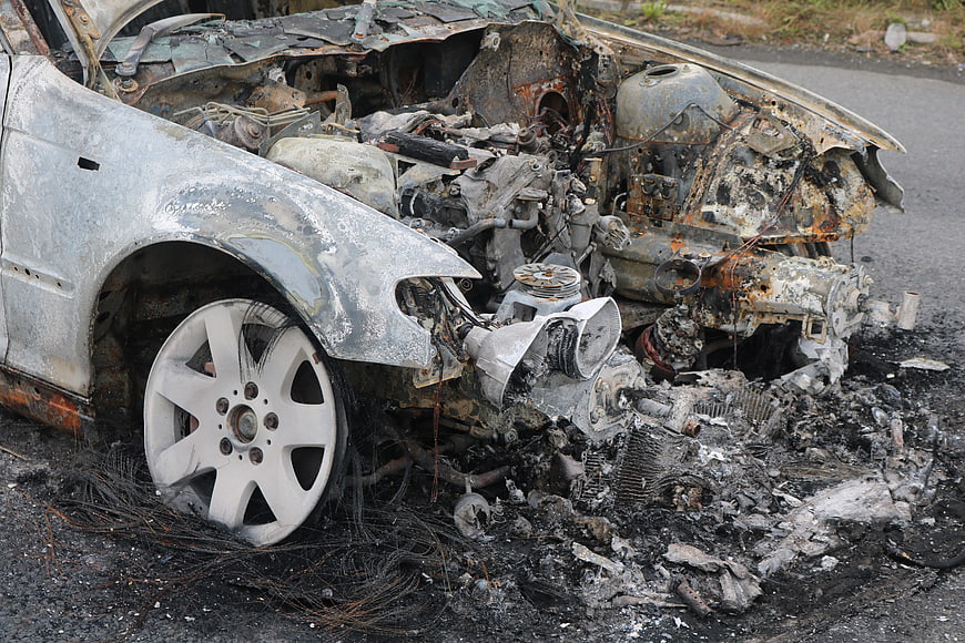 Burnt and wrecked car wreckage on asphalt road