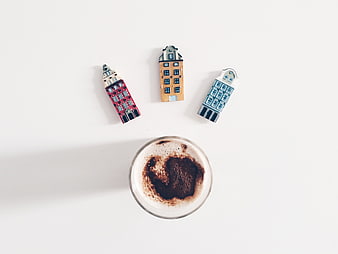 Flat lay of coffee with miniature Dutch house magnets on white background