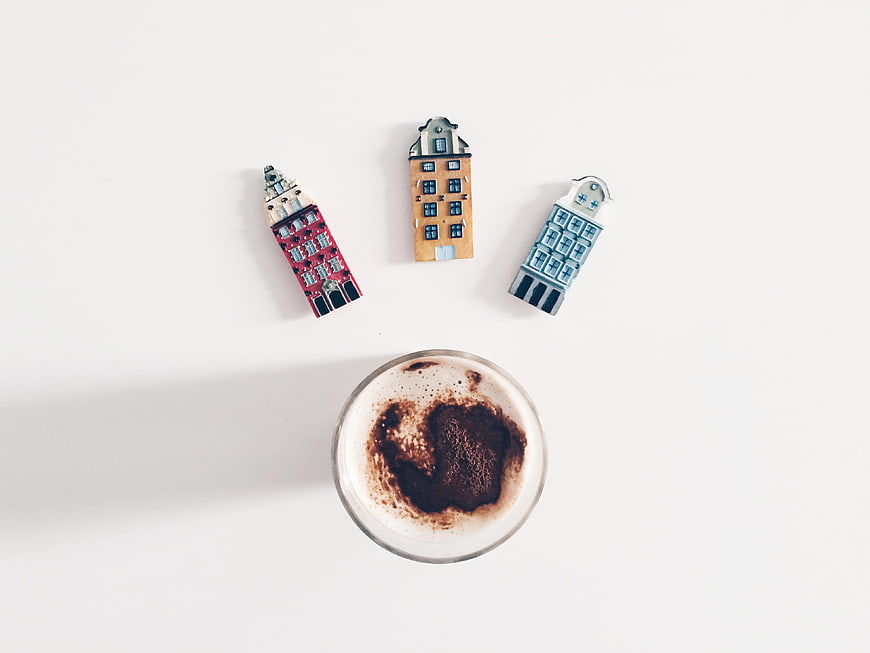 Flat lay of coffee with miniature Dutch house magnets on white background