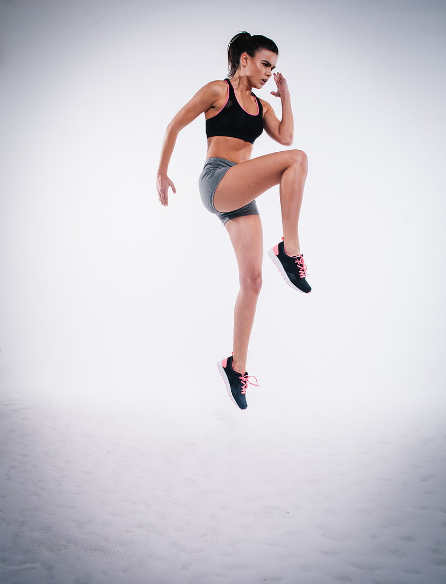 Athletic Woman Jumping in Fitness Gear on White Background