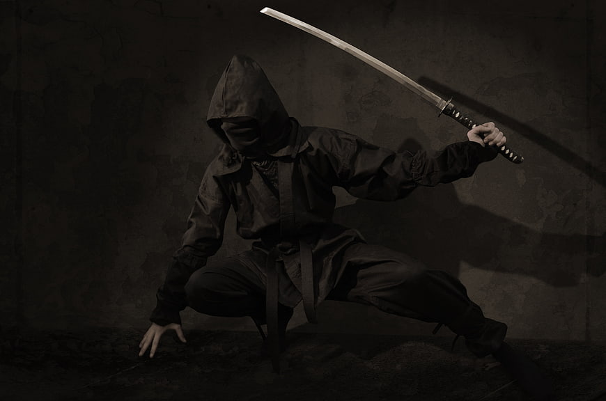 Hooded Ninja Warrior with Katana in Dark Studio