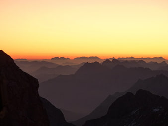 Silhouette of Mountain Ranges at Sunset with Orange Sky
