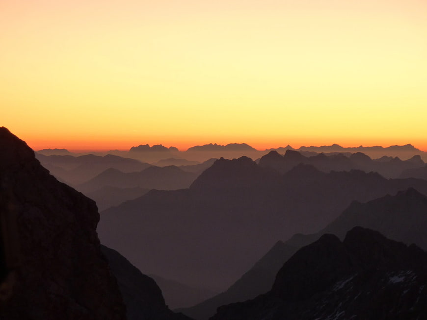 Silhouette of Mountain Ranges at Sunset with Orange Sky