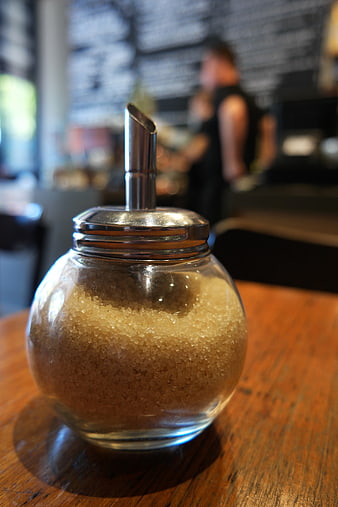 Glass Sugar Dispenser on Wooden Table in Cafe