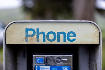 Close-up of weathered vintage public payphone sign