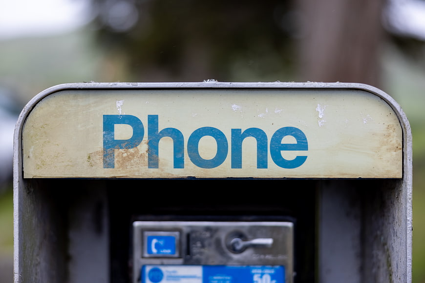 Close-up of weathered vintage public payphone sign