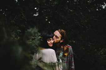 Romantic couple kissing in dark forest with film grain