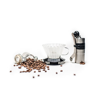 Coffee brewing setup with Kalita dripper, manual grinder, and beans